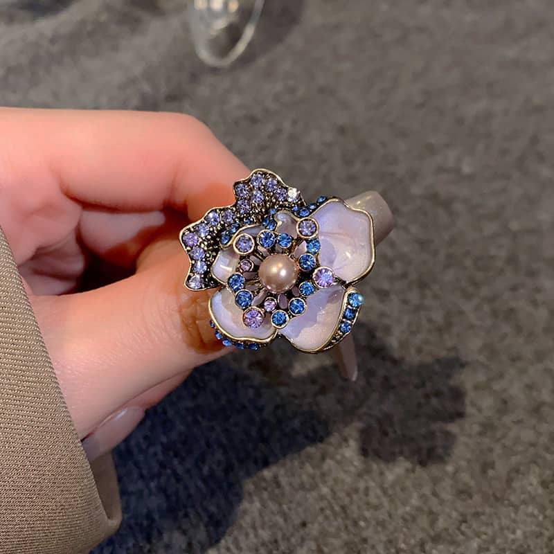 Joy ring featuring an enamel flower ring with pearl center, adorned with colorful gemstones