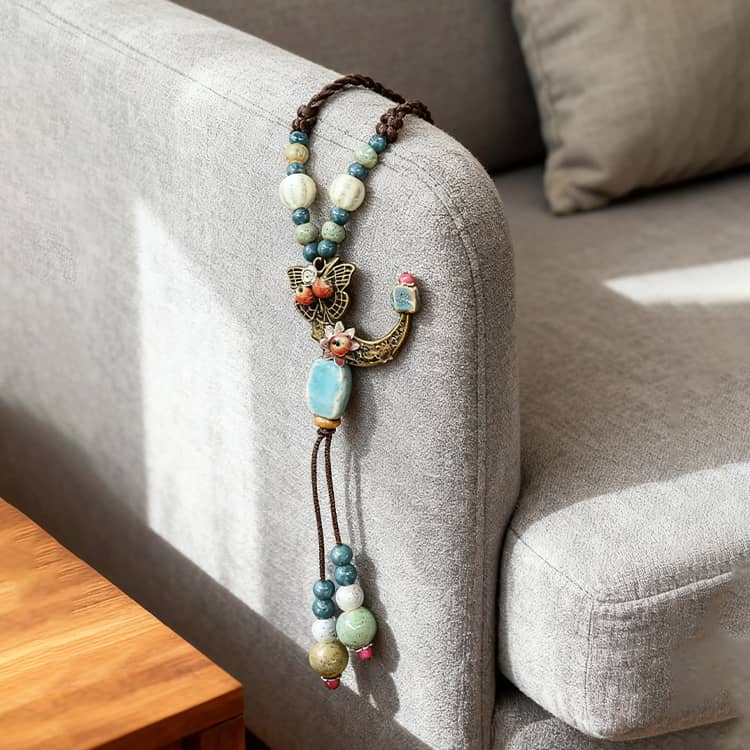Floral moon pendant necklace with natural stones and intricate detailing, displayed on a couch