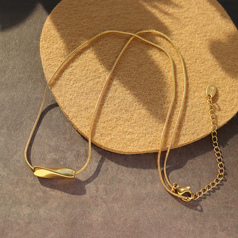Angry necklace 18K gold steel necklace with sleek curved pendant and adjustable chain on beige backdrop