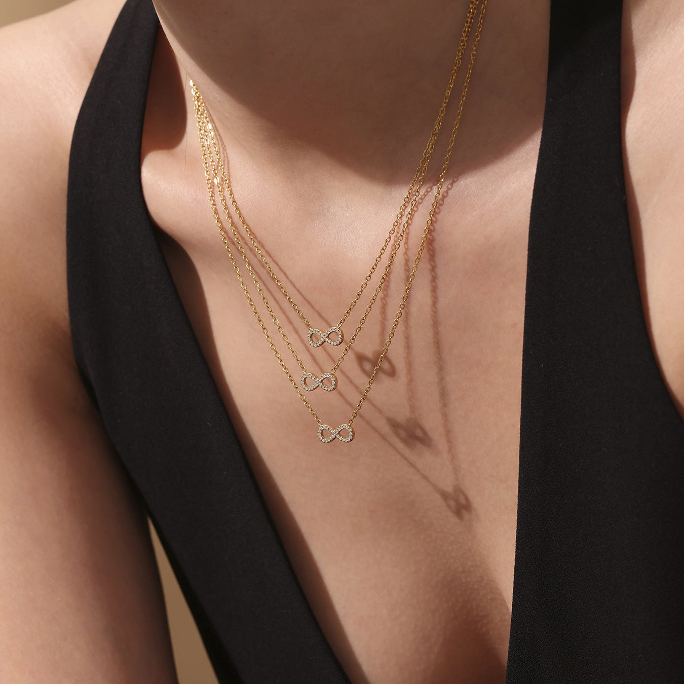 Gold layered infinity zircon necklace worn with black sleeveless top for elegant style