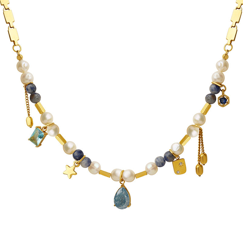 Gold chain necklace with pearls, blue stones, and assorted charms including star and teardrop pendant
