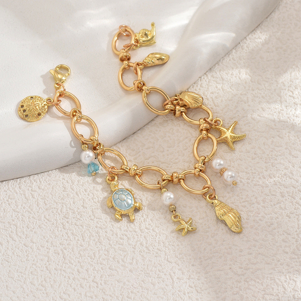 Gold sea charm bracelet with turtle starfish shell and pearl charms on gold chain