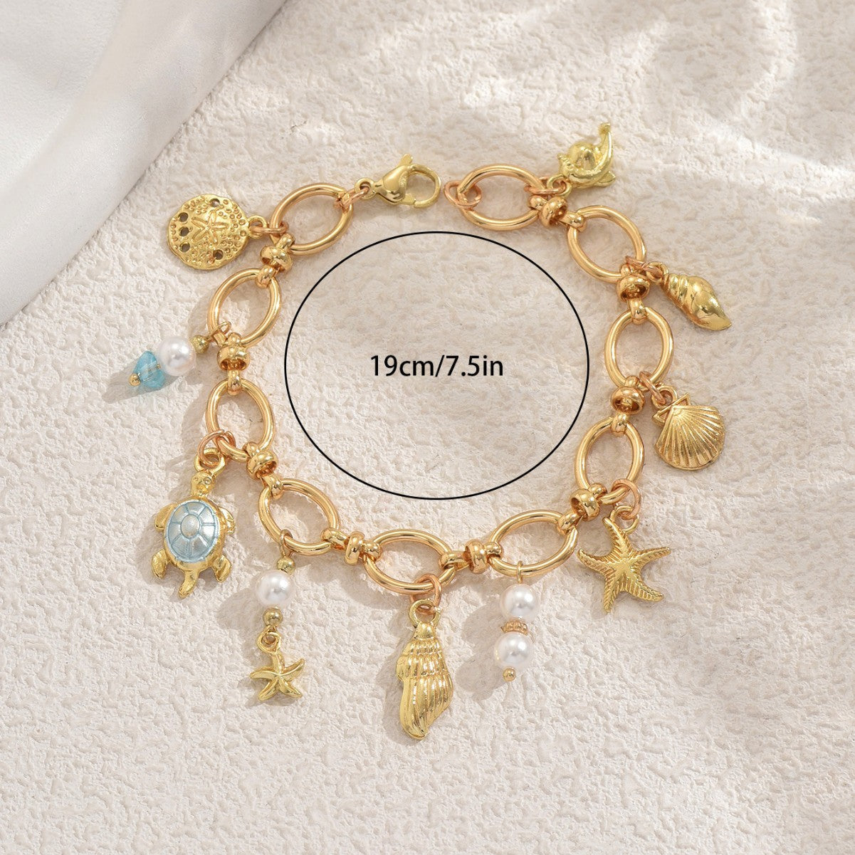 Gold sea charm bracelet with ocean-themed charms and pearls on gold links 19cm 7.5in