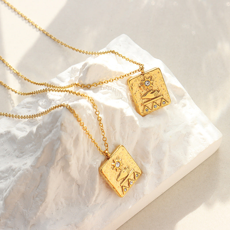 Gold solar guardian pendant necklace with engraved designs and gemstone detail on white textured display