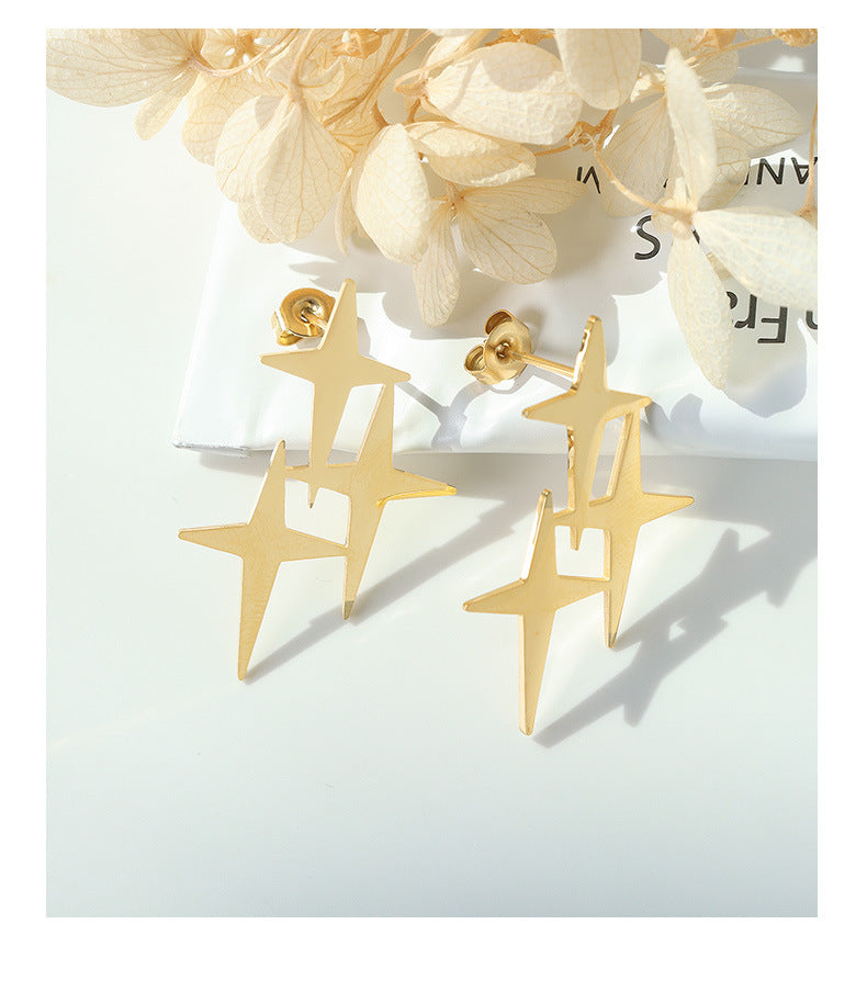 Delicate gold star stud earrings with modern abstract star design on white background