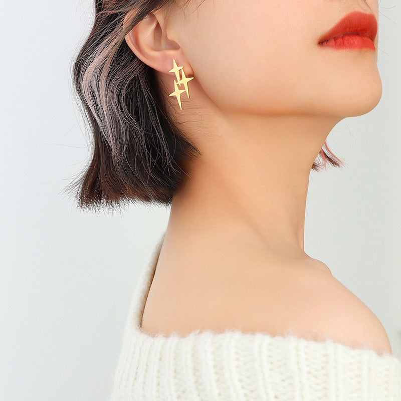 Woman wearing unique gold star stud earrings with geometric design and short hair