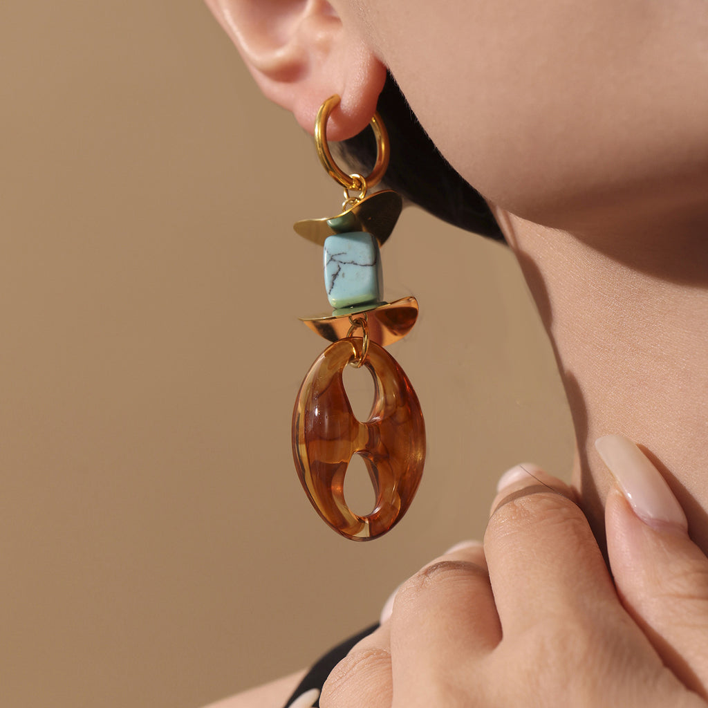Close-up of oval resin stud earrings featuring a brown oval resin and turquoise bead with gold accents