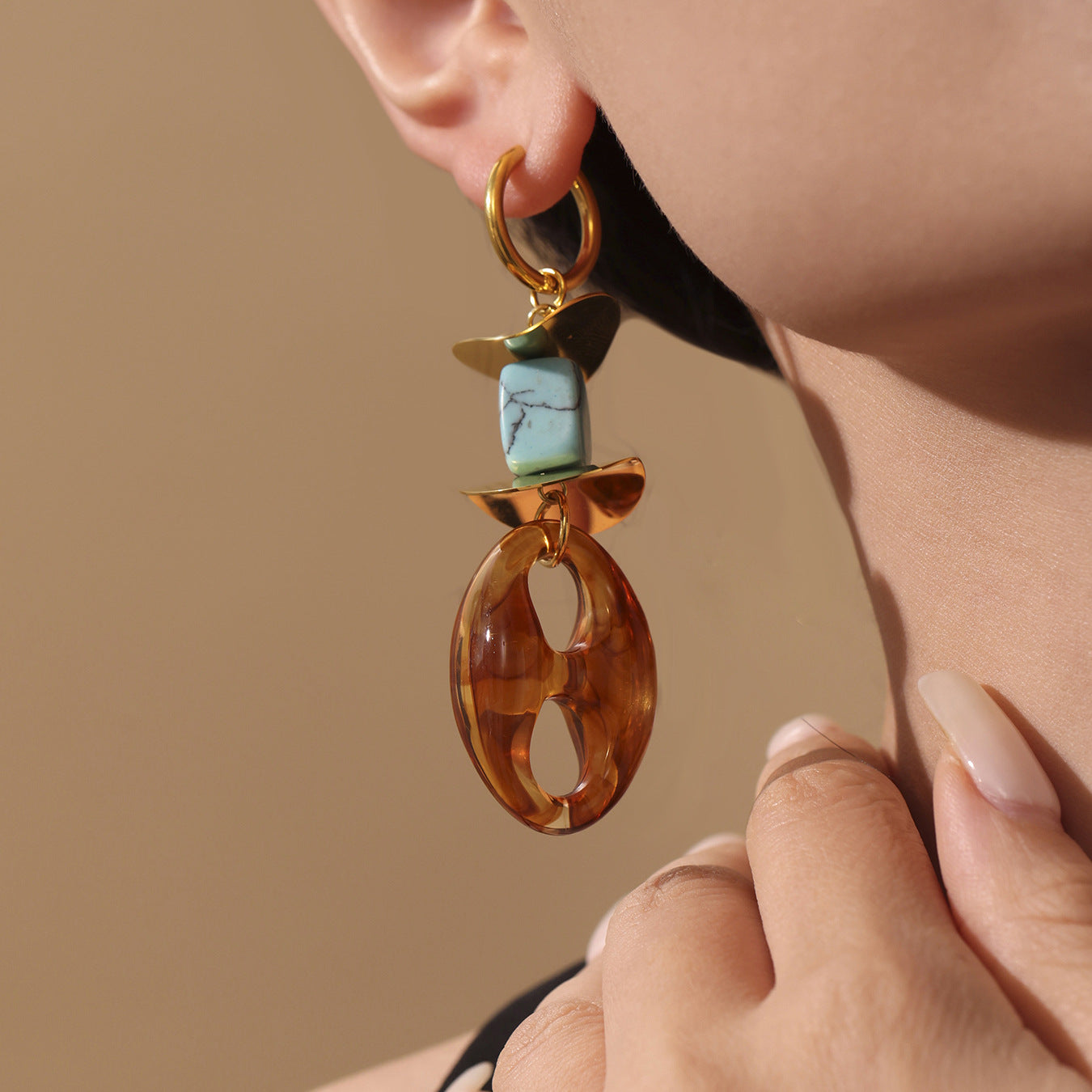 Close-up of oval resin stud earrings featuring a brown oval resin and turquoise bead with gold accents