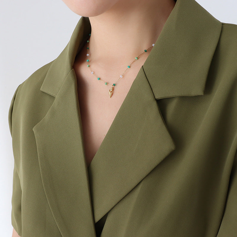 Calm necklace featuring green and clear bead jewelry with gold charm worn with olive green blazer