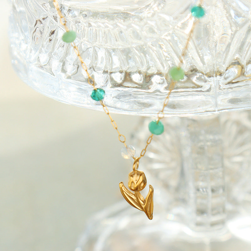 Calm necklace featuring green and clear bead jewelry with gold flower pendant on delicate chain