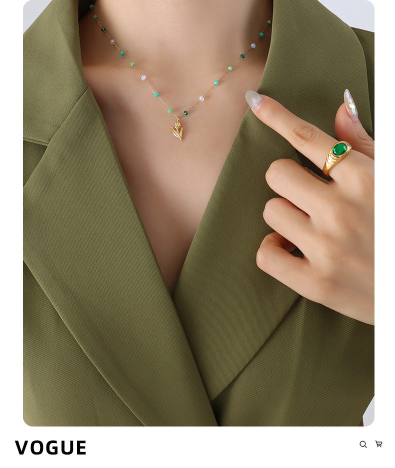 Calm necklace featuring green and clear bead jewelry worn with olive green blazer and gold ring