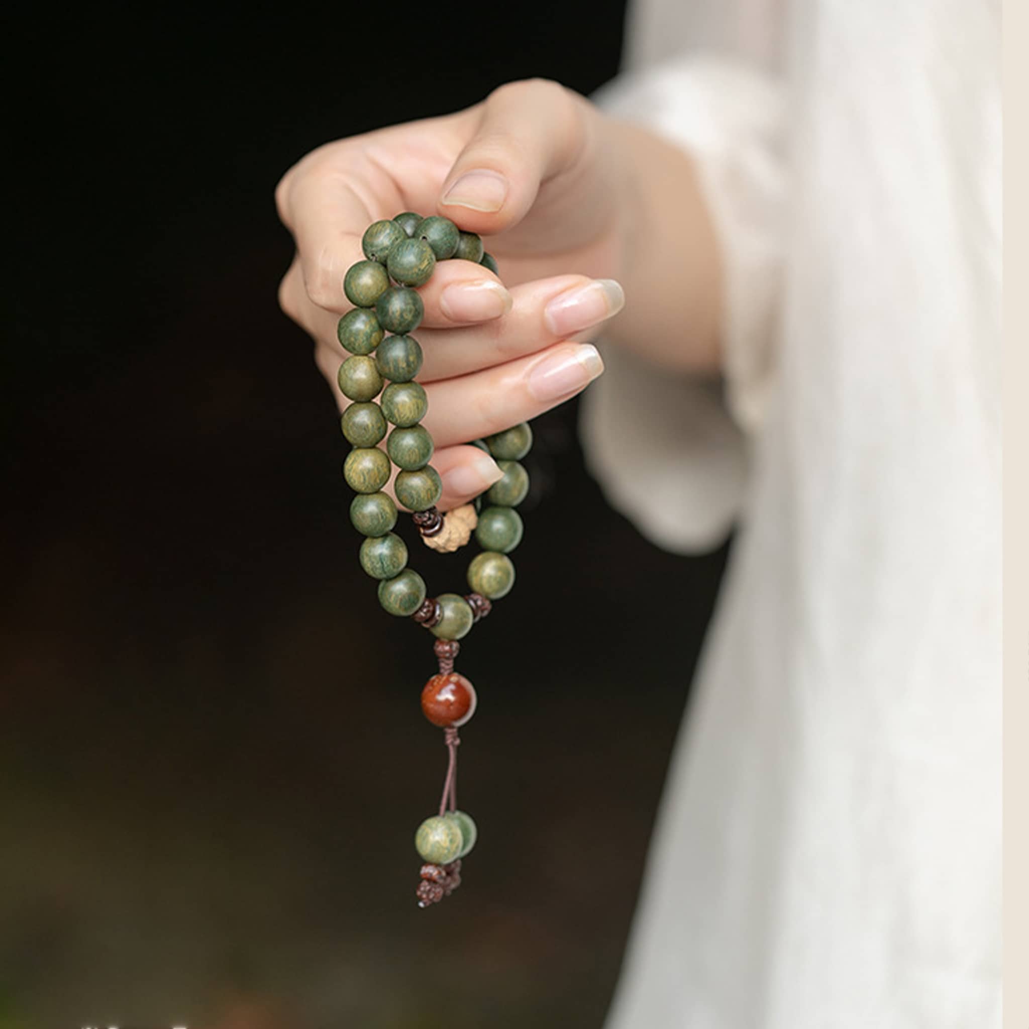 Calm green sandalwood mala bracelet held in hand, featuring earthy green beads for meditation and relaxation