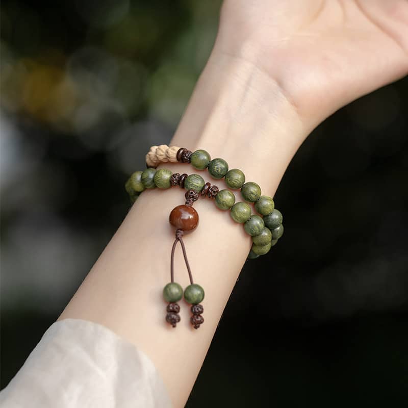 5 Senses green sandalwood mala bracelet on a wrist featuring natural beads and tassel design
