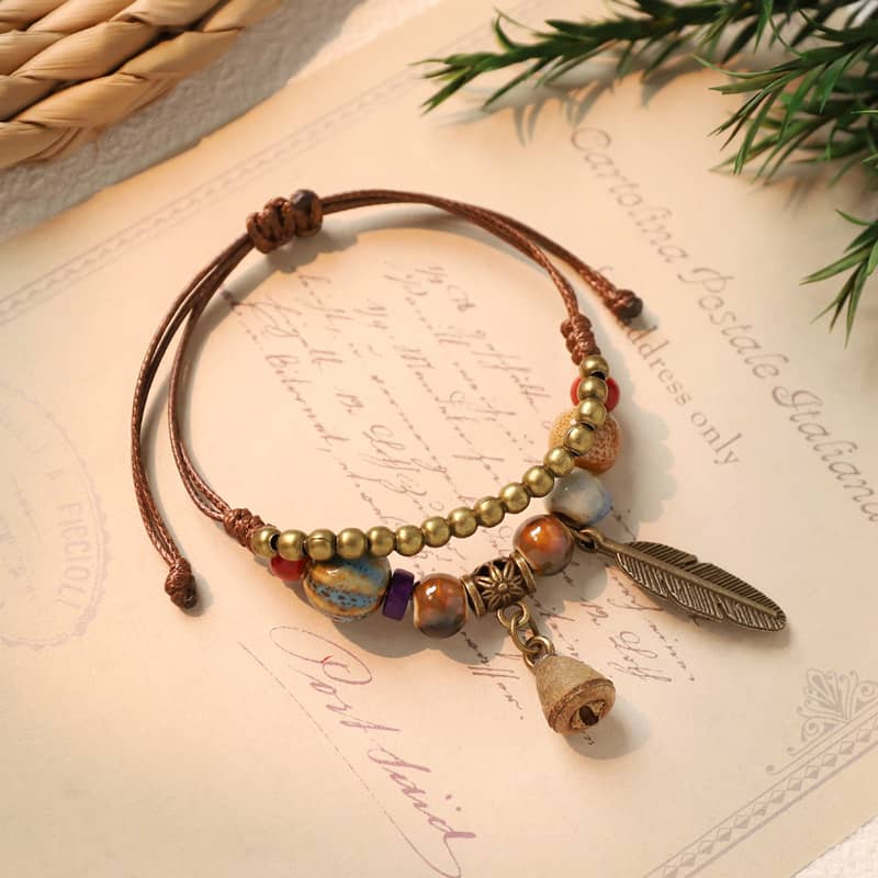 Handmade bell and bead bracelet with natural beads and feather charm for a unique accessory