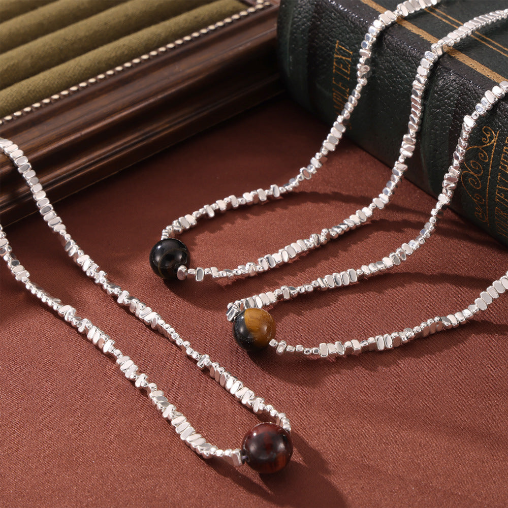Healing crystal necklace silver chain with various round gemstone pendants on a brown surface