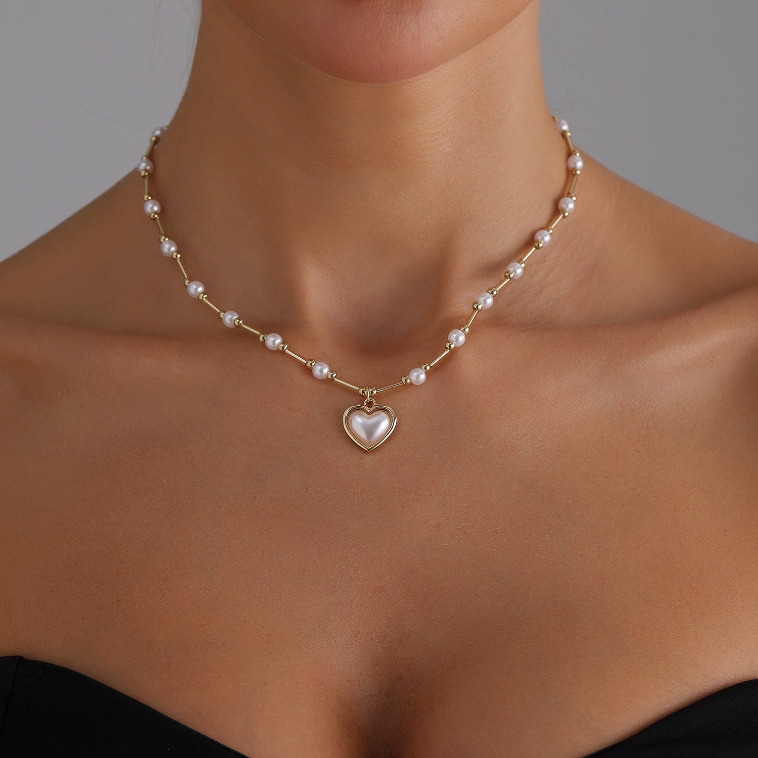 Elegant heart pearl necklace with gold chain and white pearls worn on neck