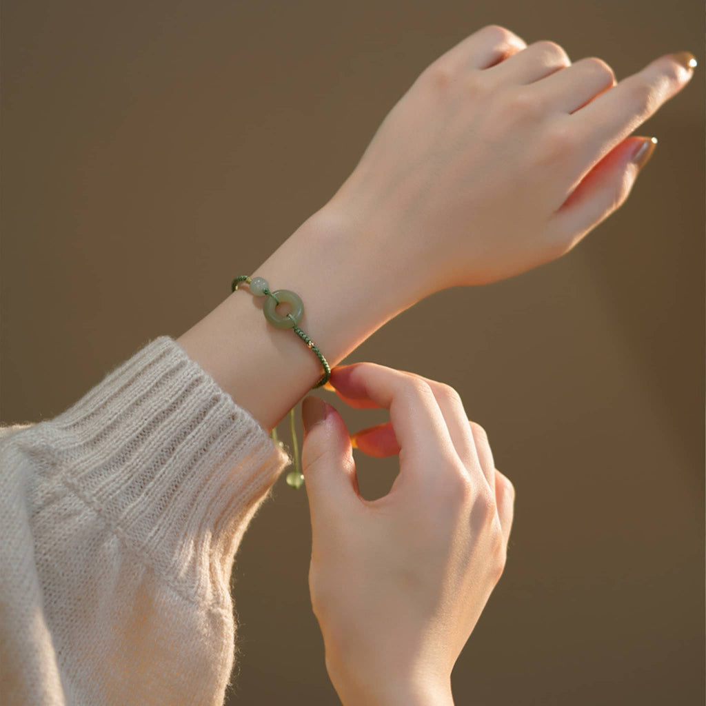 Hetian jade peace buckle bracelet worn on a wrist with a cozy sweater background