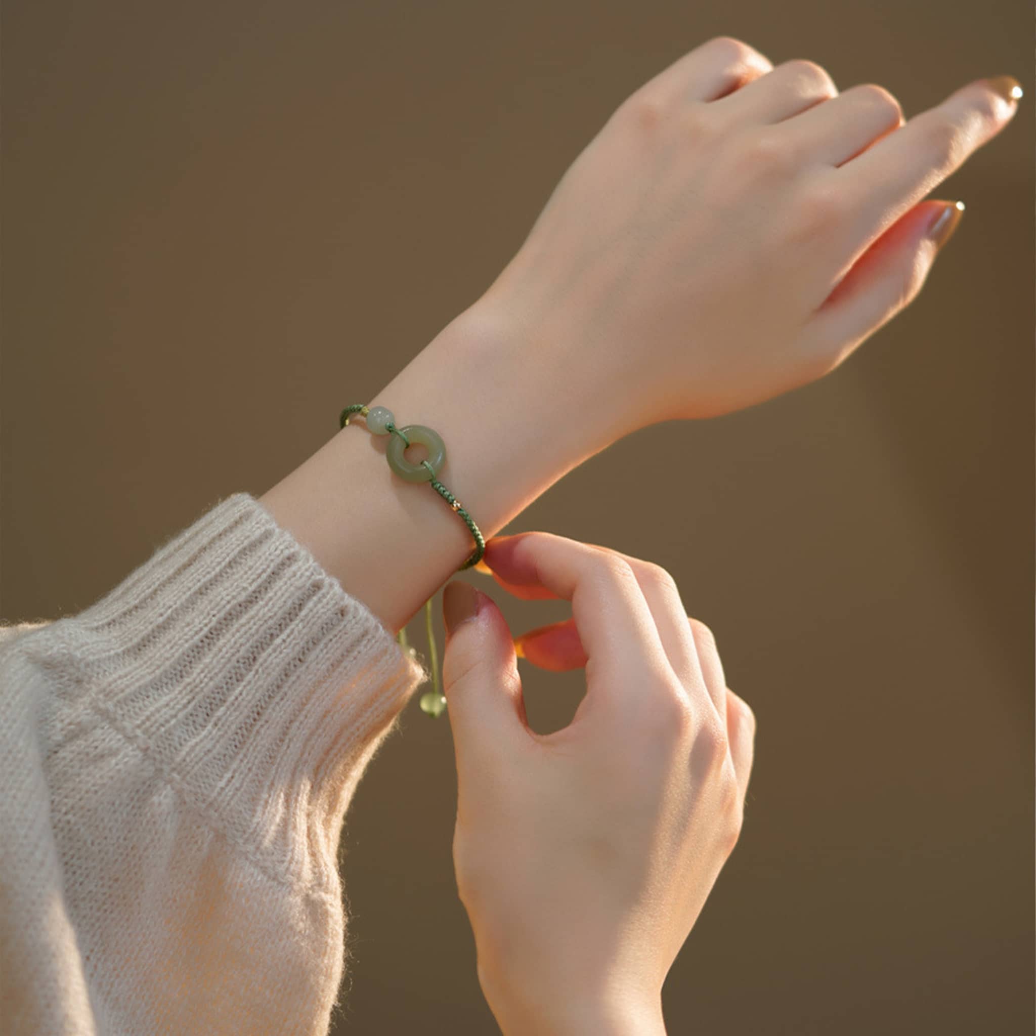 Hetian jade peace buckle bracelet worn on a wrist with a cozy sweater background