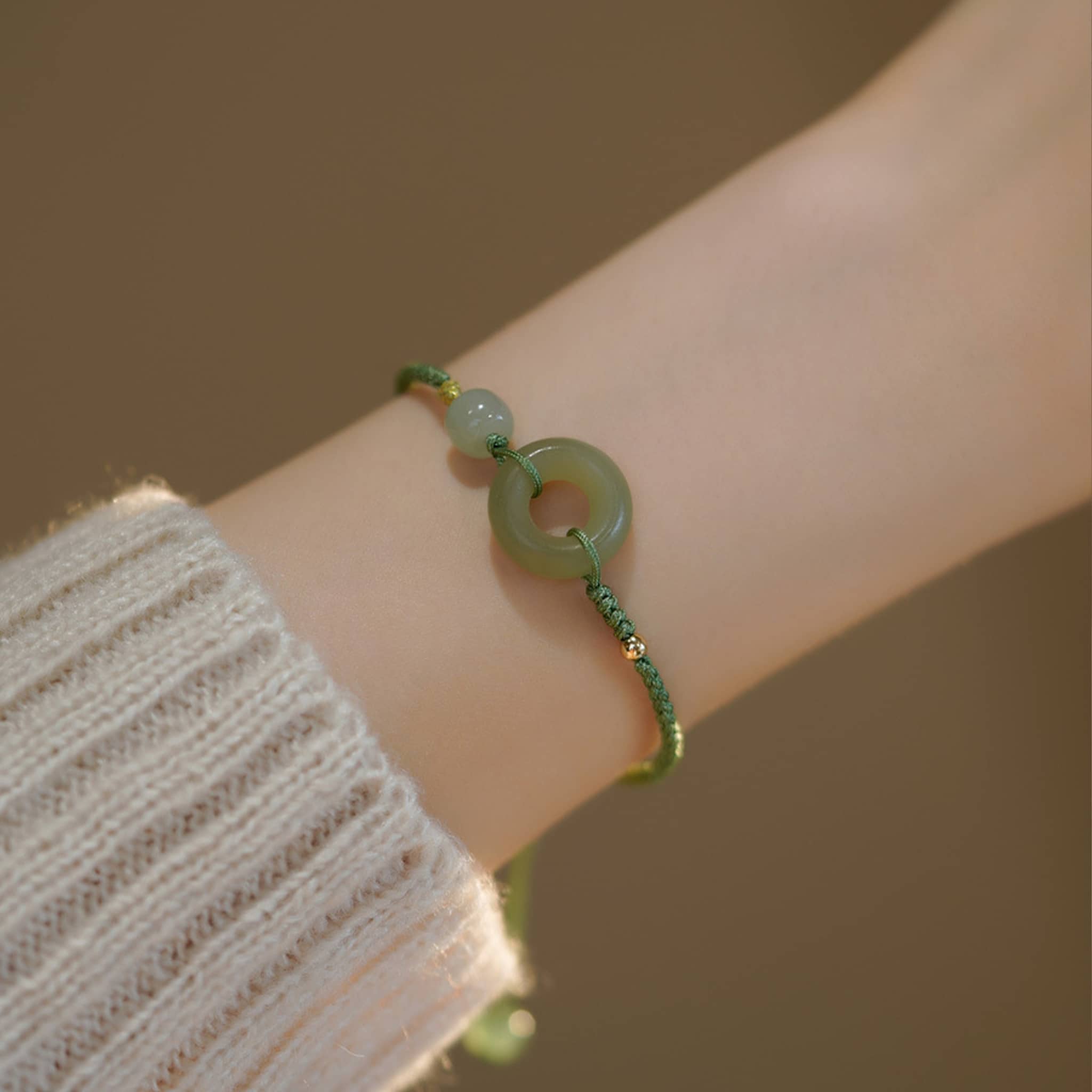 Hetian jade peace buckle bracelet on a wrist with a green cord and beads for a calming effect