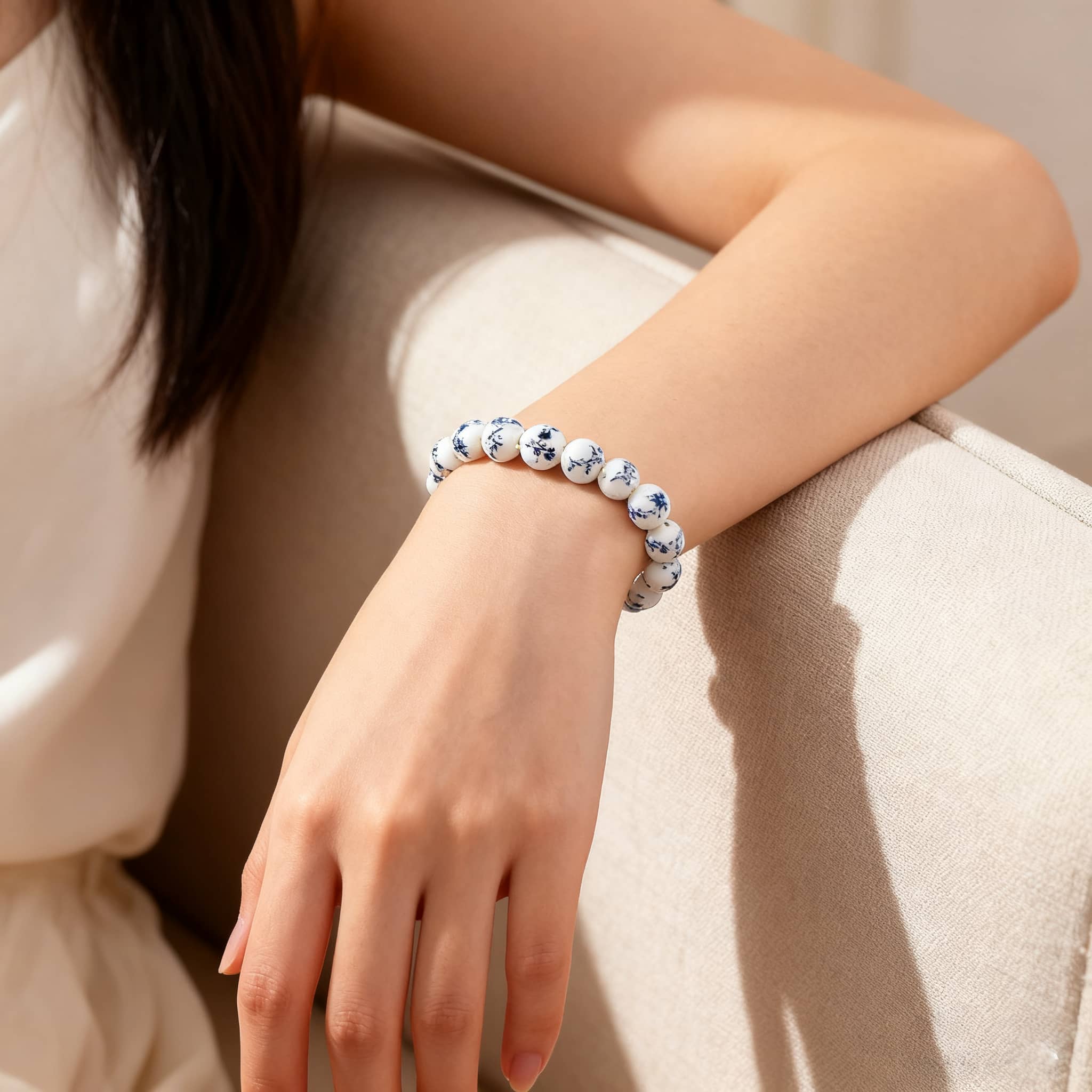 Woman wearing an ink splash porcelain bracelet with blue designs on a white background