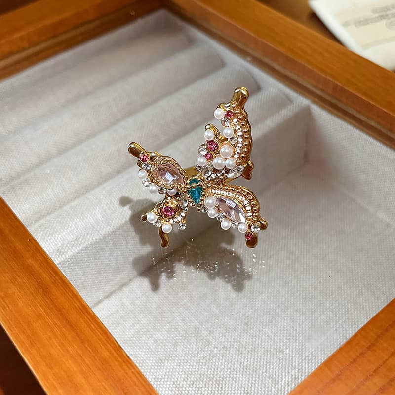 Joyful butterfly statement ring with colorful gemstones and elegant pearl accents in a display box