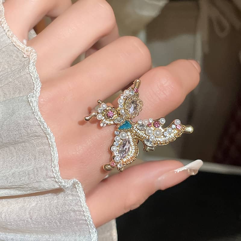 Joyful butterfly statement ring with colorful gemstones set on a hand wearing a light fabric sleeve