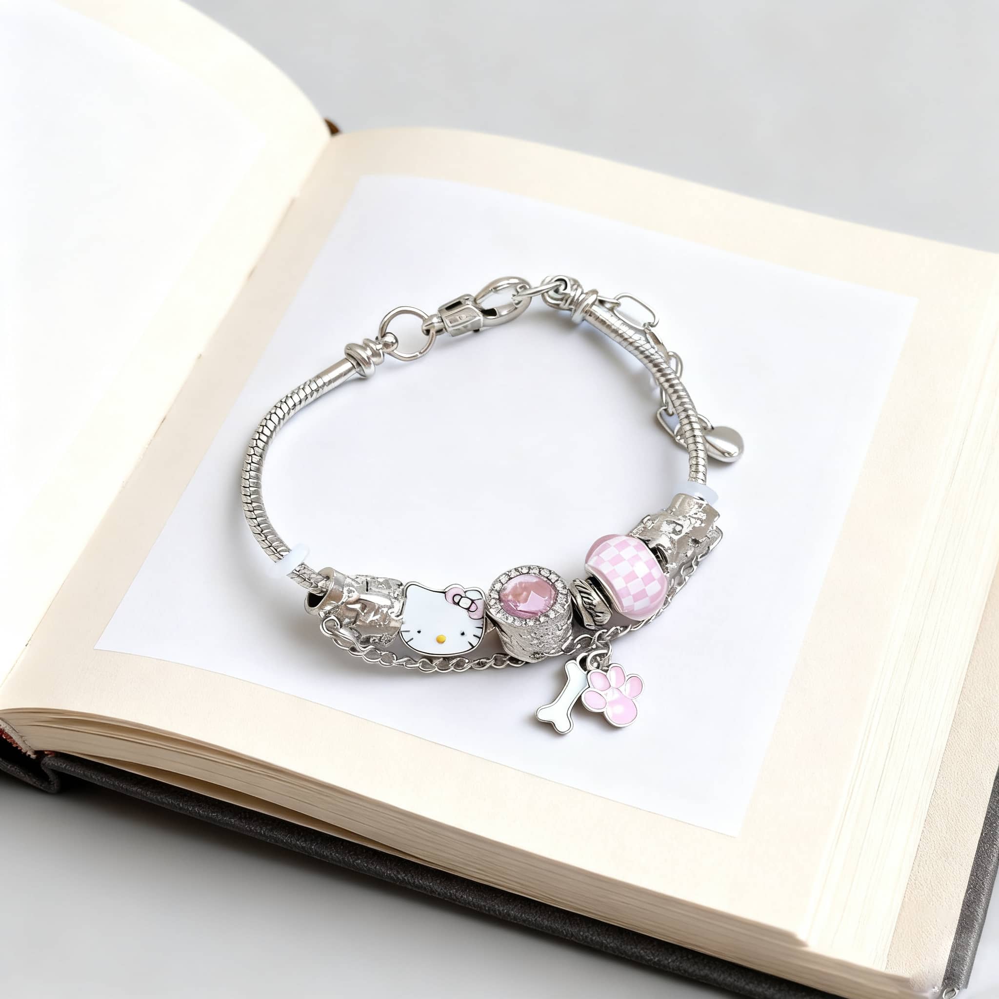 Joyful cat charm bracelet with pink accents displayed on an open book