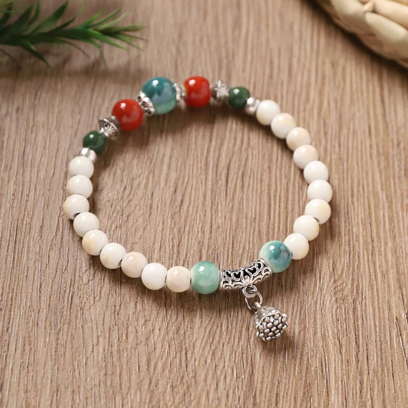 Lotus ceramic bracelet for self care with colorful beads and decorative charm on a wooden surface