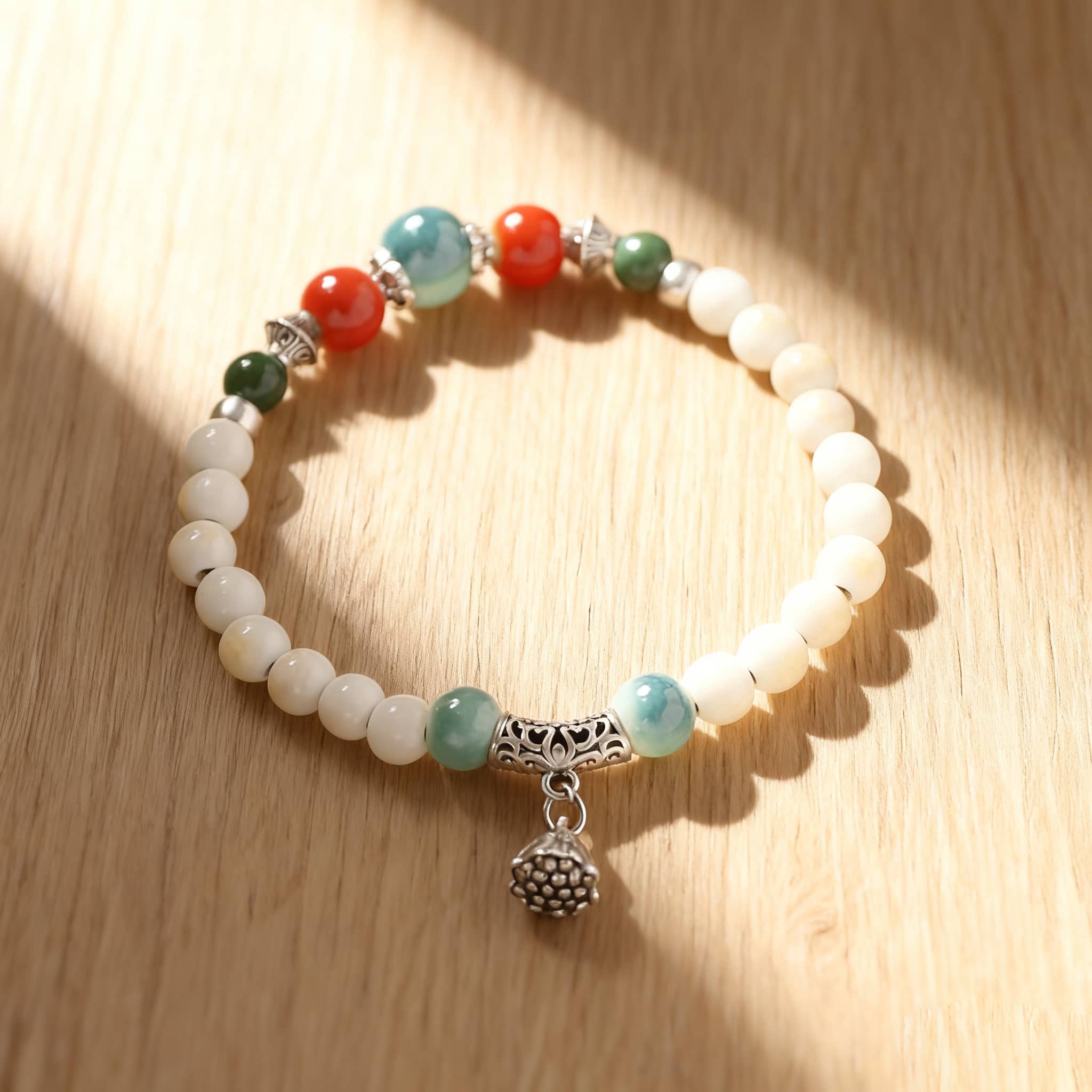 Lotus ceramic bracelet for self care featuring colorful beads and a silver charm on a wooden background