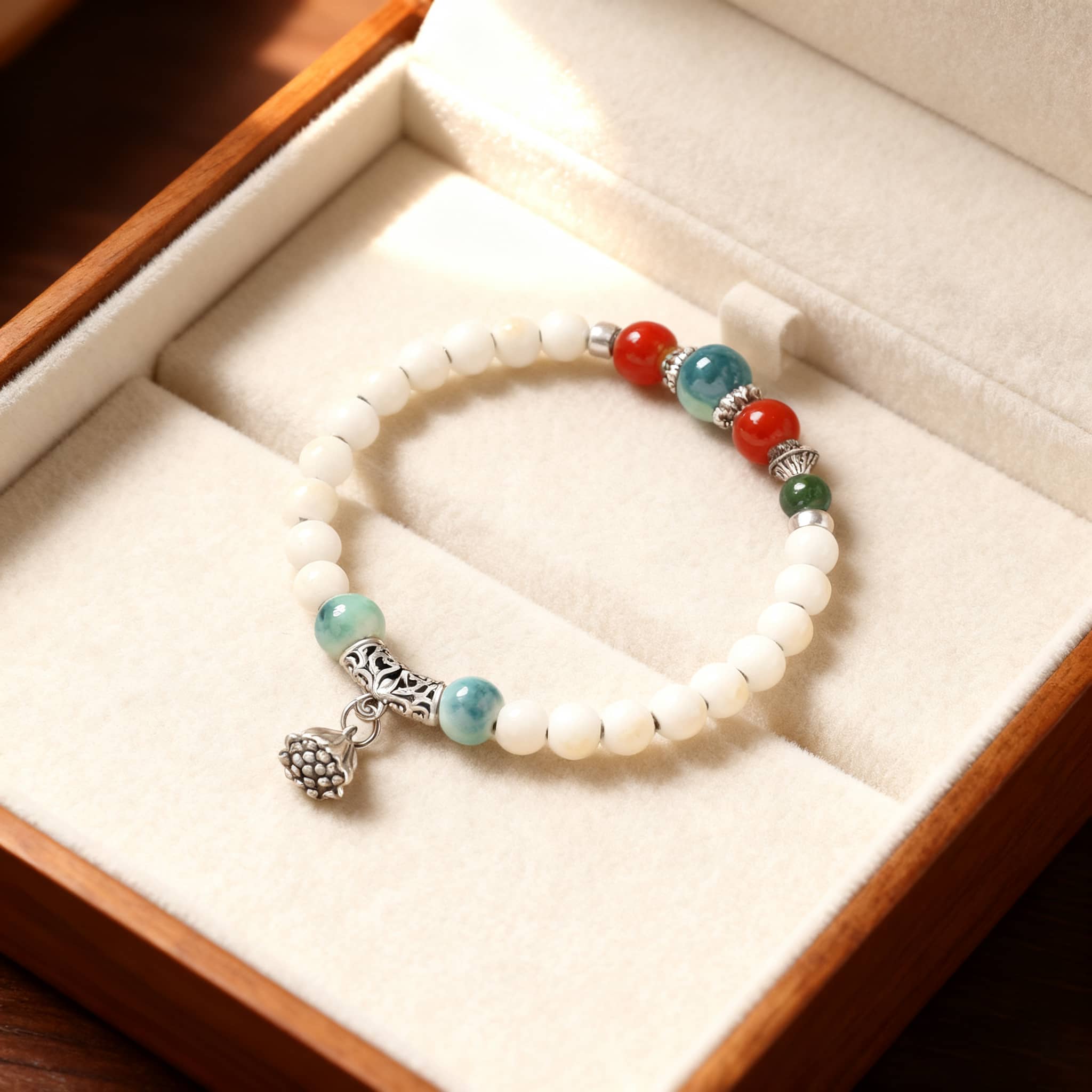 Lotus ceramic bracelet for self care with colorful beads and silver charm displayed in a wooden box