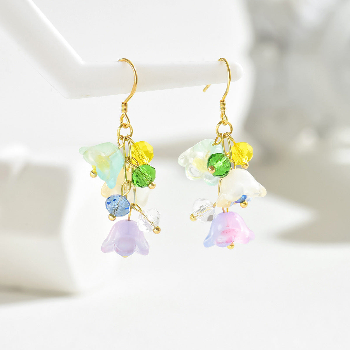 colorful floral stud earrings inspired design shown as delicate dangle earrings with pastel glass flowers and gold hooks