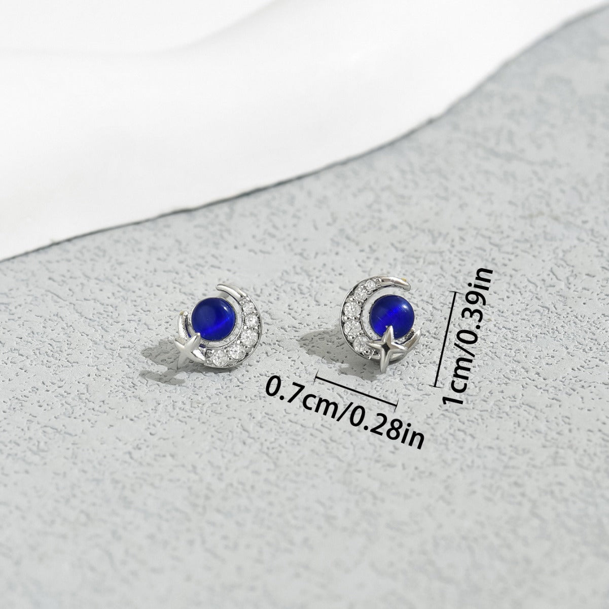 Delicate sterling silver crescent moon star stud earrings with deep blue cabochon center and cubic zirconia accents