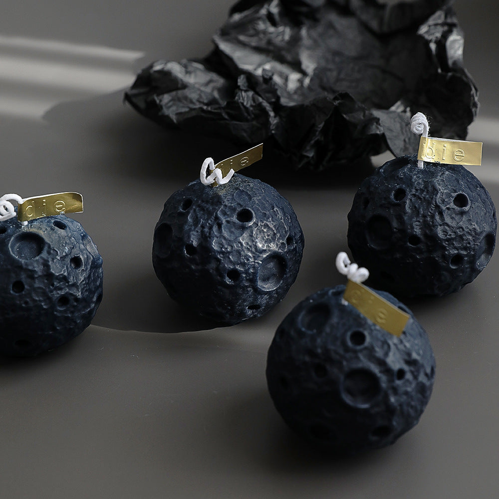 Set of four black lunar soy candles shaped like the moon with crater details and gold tags