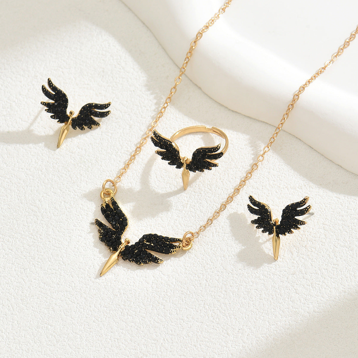 black angel wings jewelry set featuring gold chain necklace matching ring and two stud earrings with glitter finish