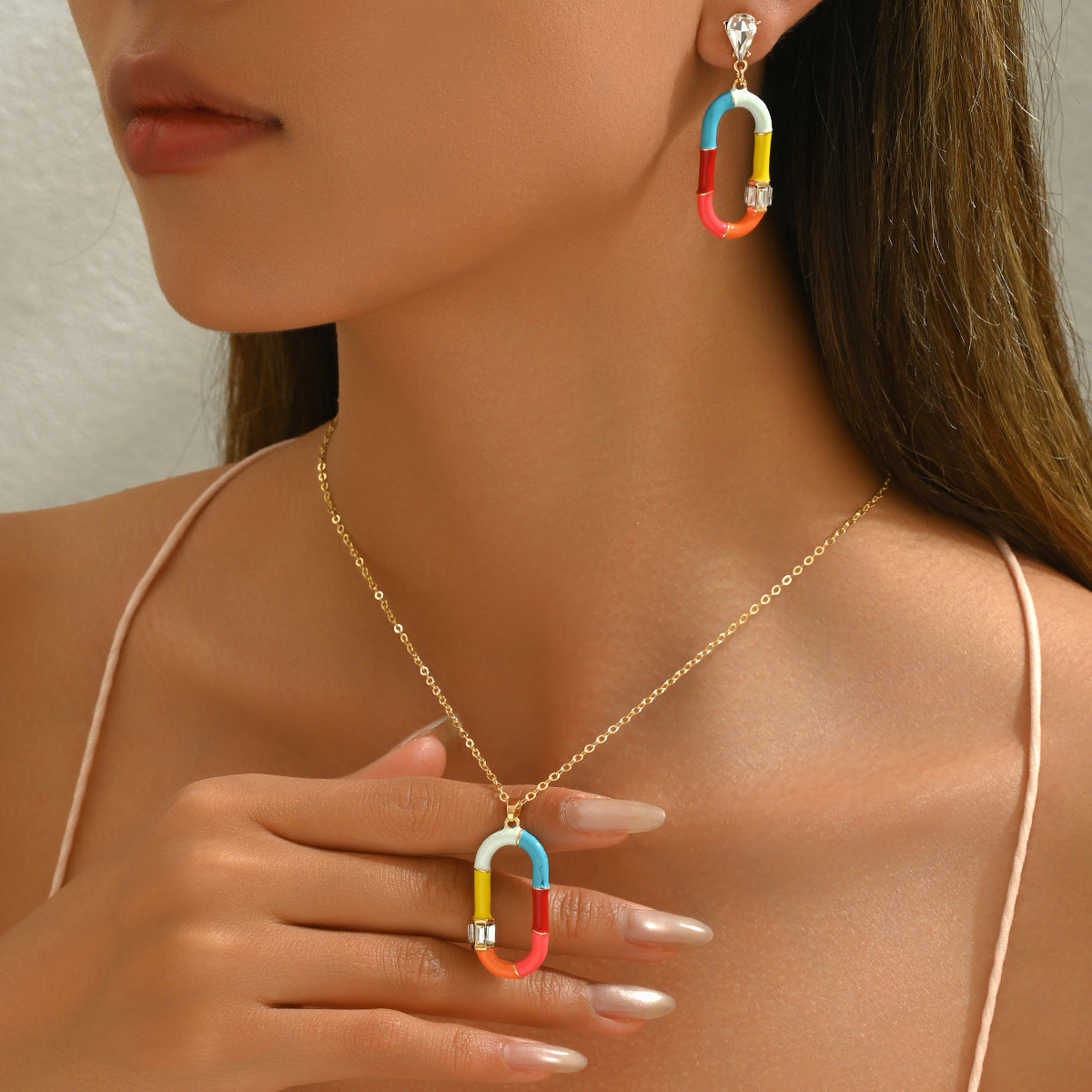 Woman wearing Joy colorful enamel necklace with gold chain and matching multicolor enamel oval pendant and earring