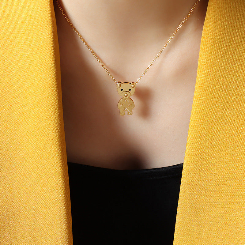 Woman wearing golden teddy bear necklace with delicate gold chain pendant styled with yellow blazer and black top