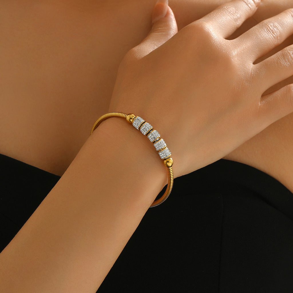 Close up of a woman wearing a golden geometric magnetic bracelet with sparkling crystal cube beads on gold chain