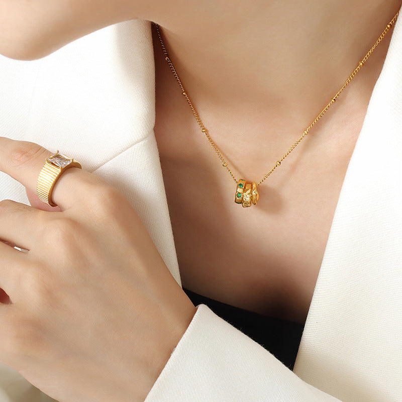 Gold necklace with small green and clear stones worn as meaningful jewelry for anxiety