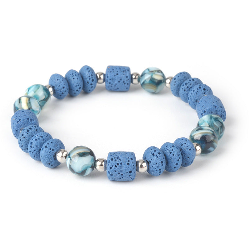 Mens healing lava rock bracelet with blue porous stones and silver beads on white background