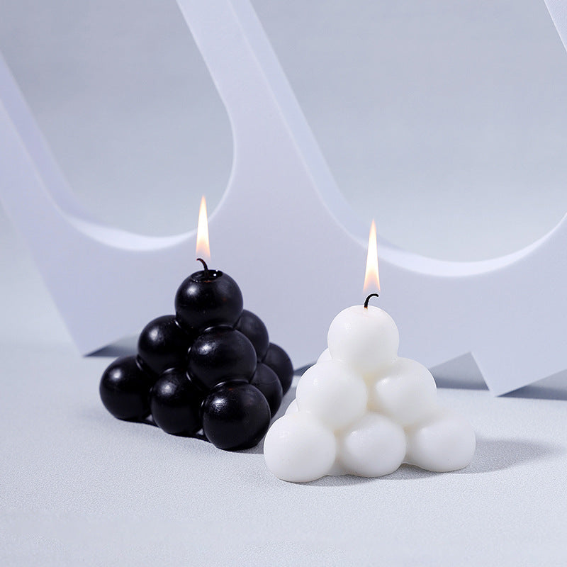 Black and white modern decorative aromatherapy candle shaped in pyramid of spheres burning with soft flames