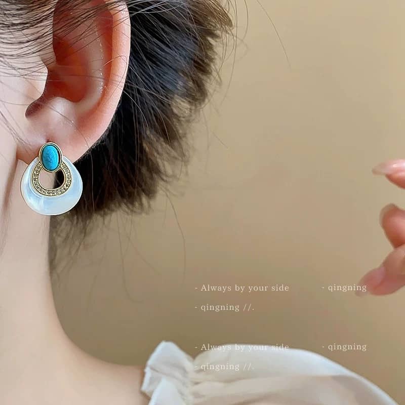 Elegant mother-of-pearl and blue turquoise earrings displayed on a model's ear for a stylish look