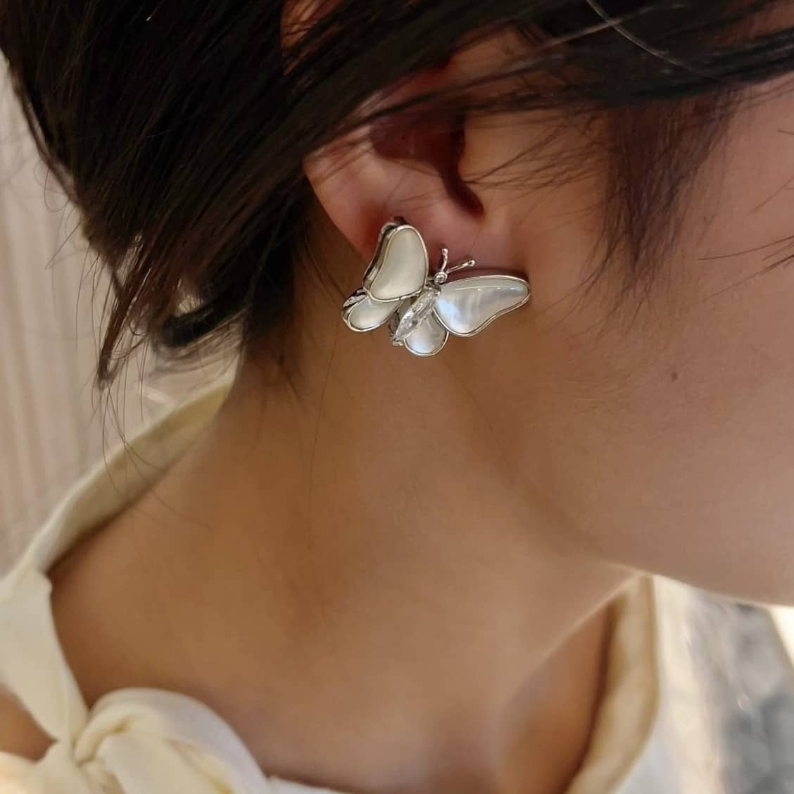 Elegant mother of pearl butterfly earrings showcased on a model's ear, perfect for chic occasions