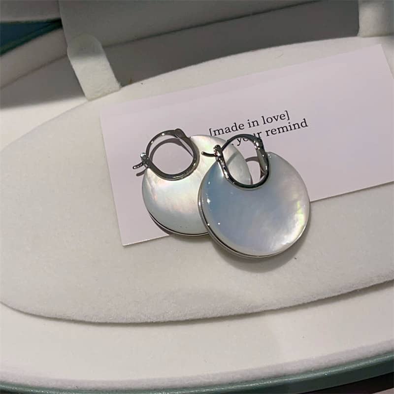 Elegant mother of pearl ear cuffs with shiny surface displayed in a soft jewelry box