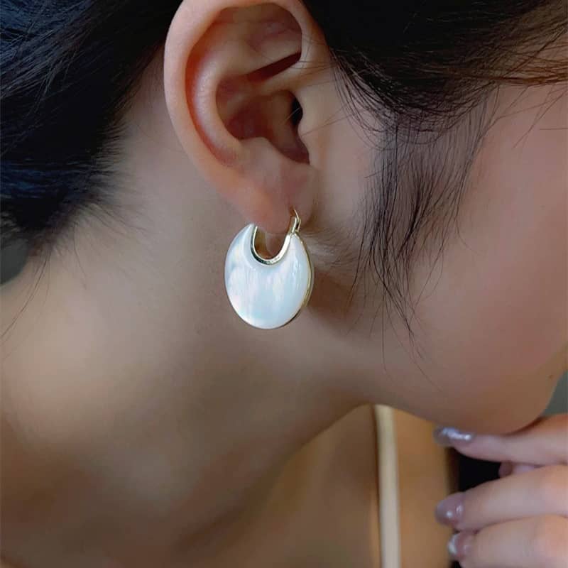 Elegant mother of pearl ear cuffs showcased on a model's ear for a stylish look