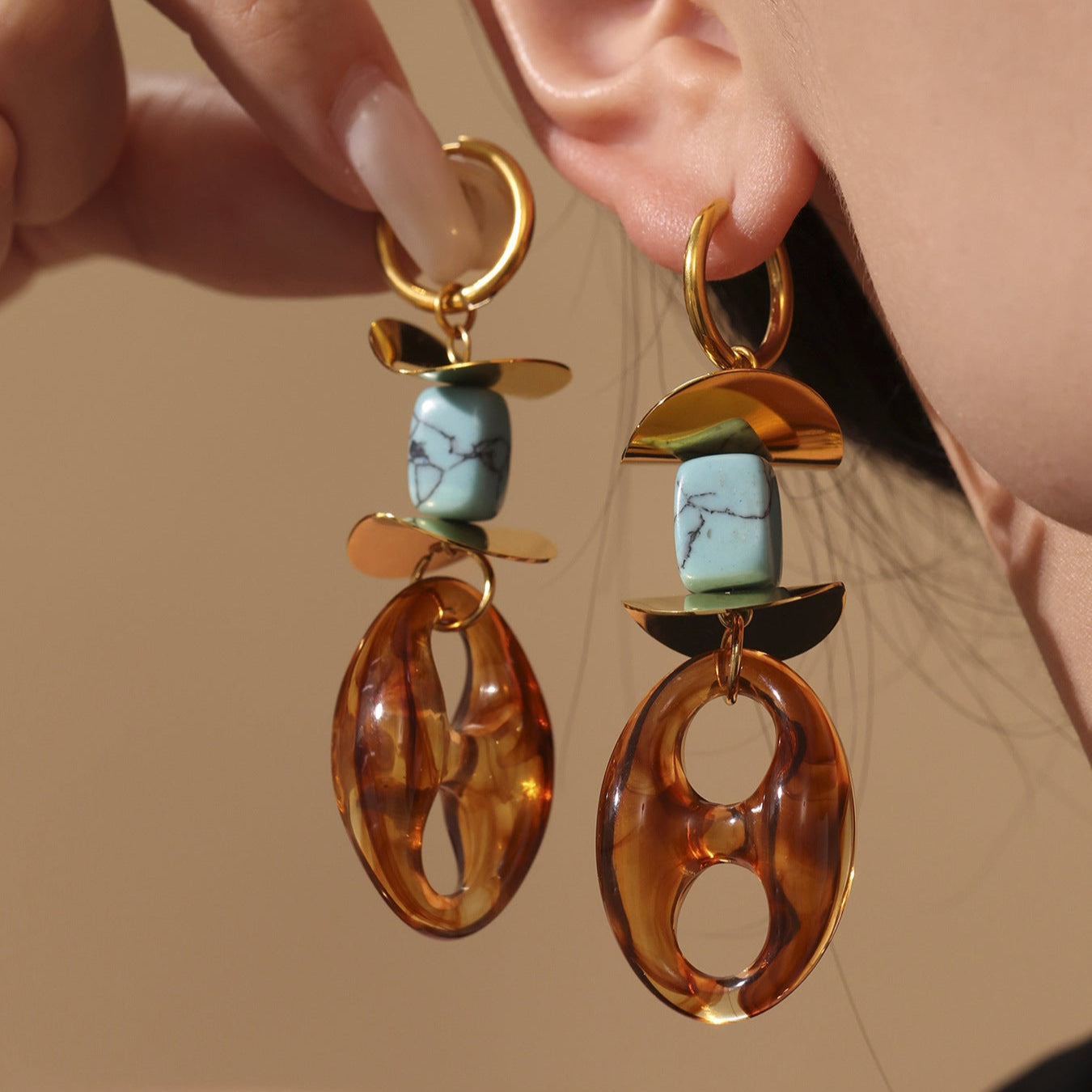 Calm oval resin stud earrings with turquoise stone and gold accents worn on ear