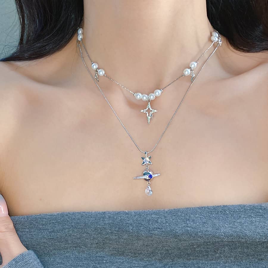 Elegant pearl and Saturn pendant necklace layered with delicate silver chains