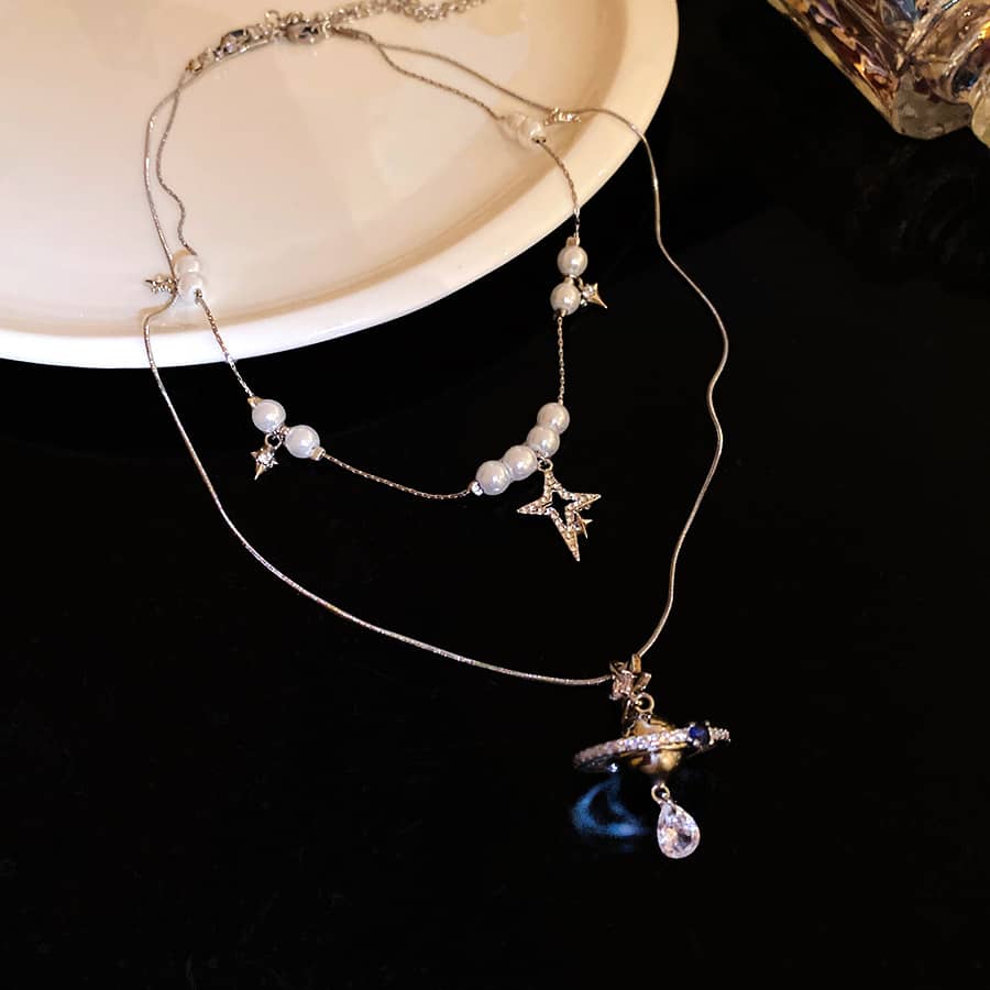 Elegant pearl and Saturn pendant necklace with star accents for a touch of celestial charm
