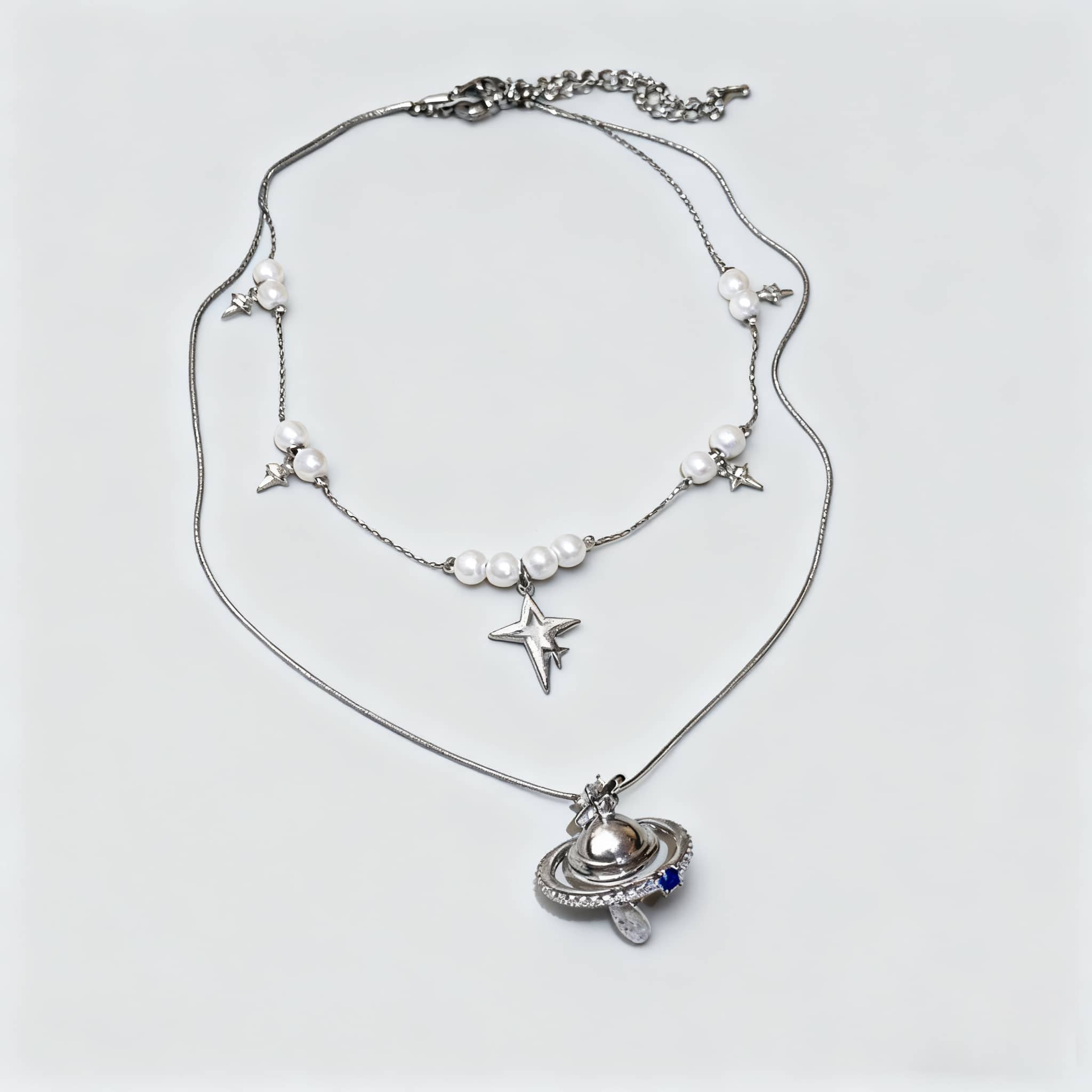 Elegant pearl and Saturn pendant necklace featuring silver stars and a celestial design