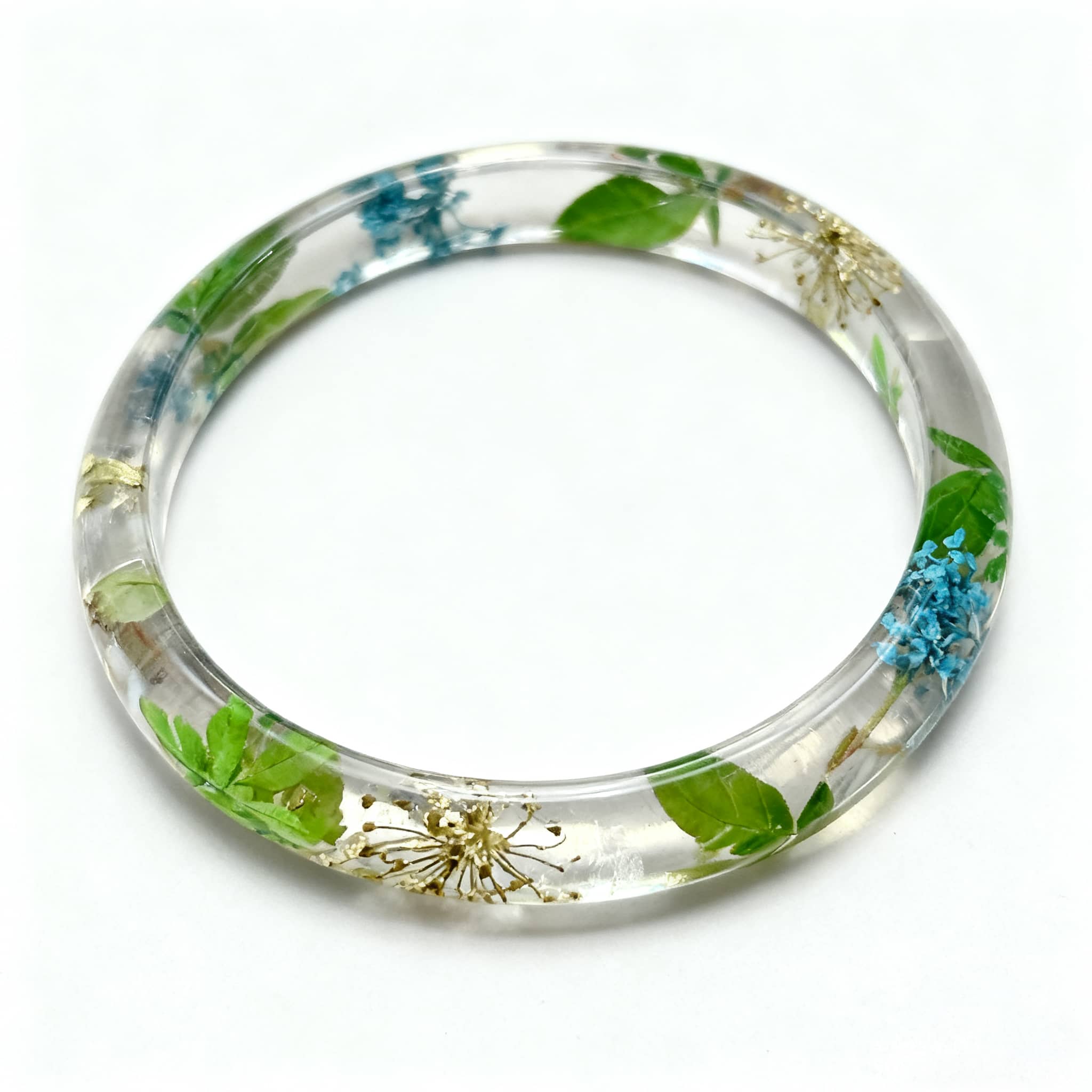 Preserved flower resin bracelet featuring vibrant green leaves and delicate flowers inside a clear bangle