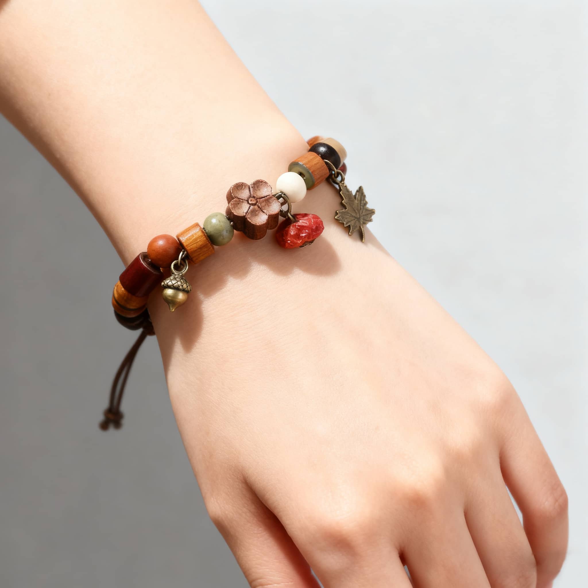 Hand wearing a red berry wood bead bracelet featuring colorful beads and decorative charms